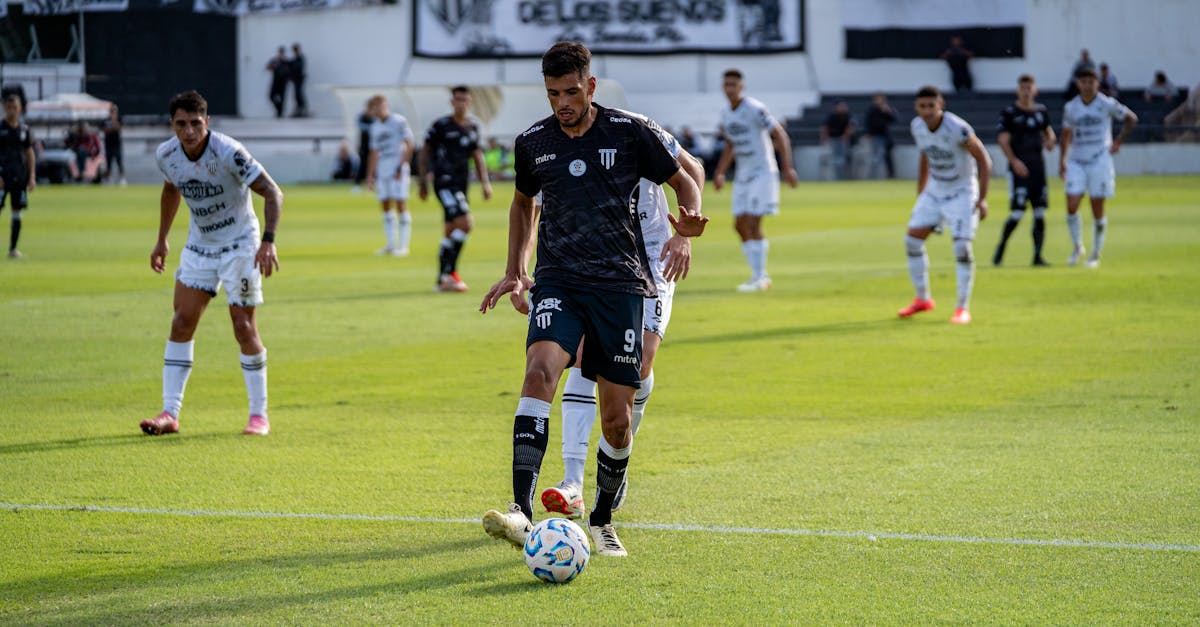 A soccer player controls the ball during an intense outdoor match on a sunny day.