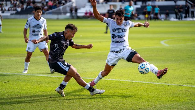 Players compete fiercely in a live soccer match on a sunny field.
