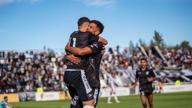 Two soccer players embracing in celebration on the field during a match.