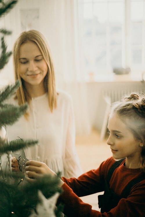 Two Girls Putting Decorations On A Christmas Tree