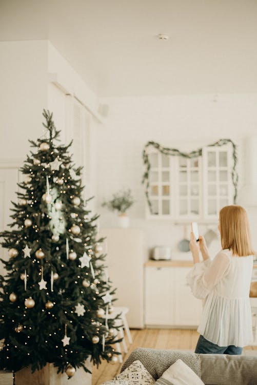 Woman Taking Photo Of Christmas Tree