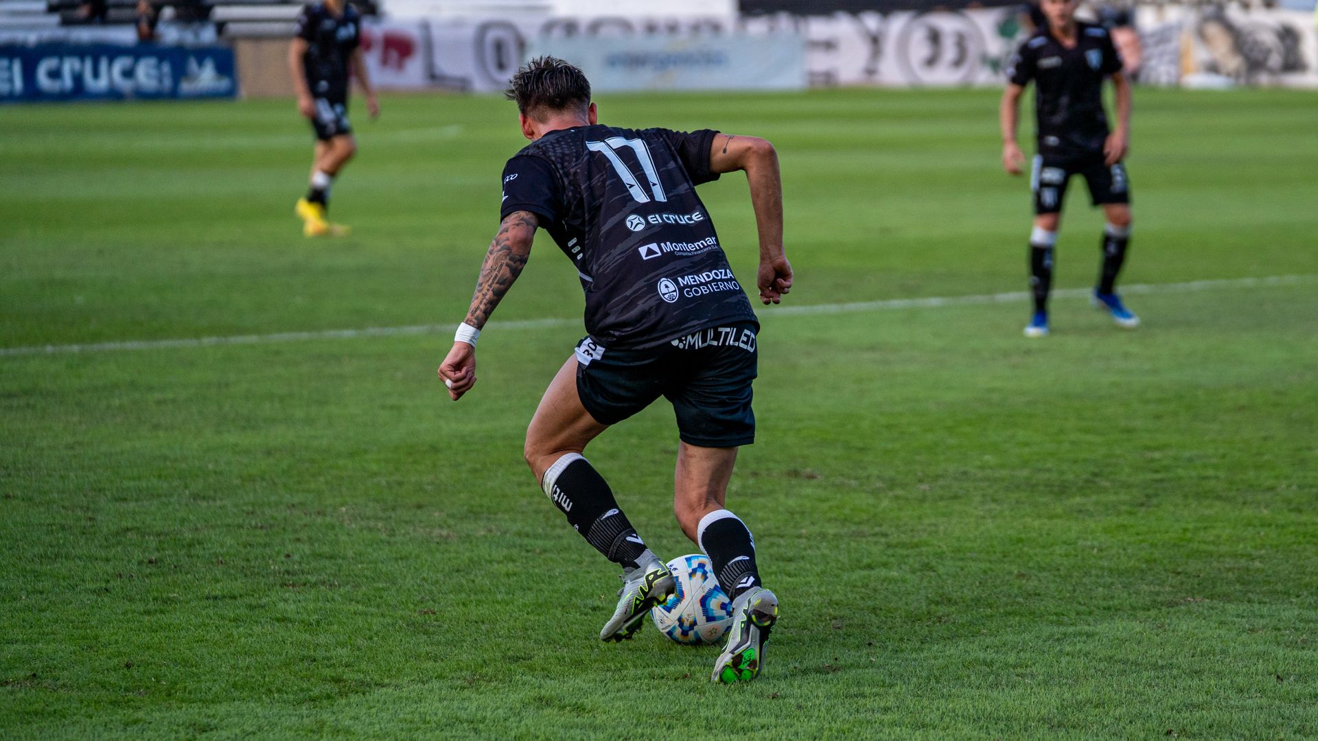 A football player in action dribbling the ball during a match on a grassy field.
