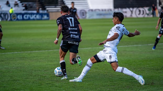 Two soccer players in action during an intense match on the grass field.