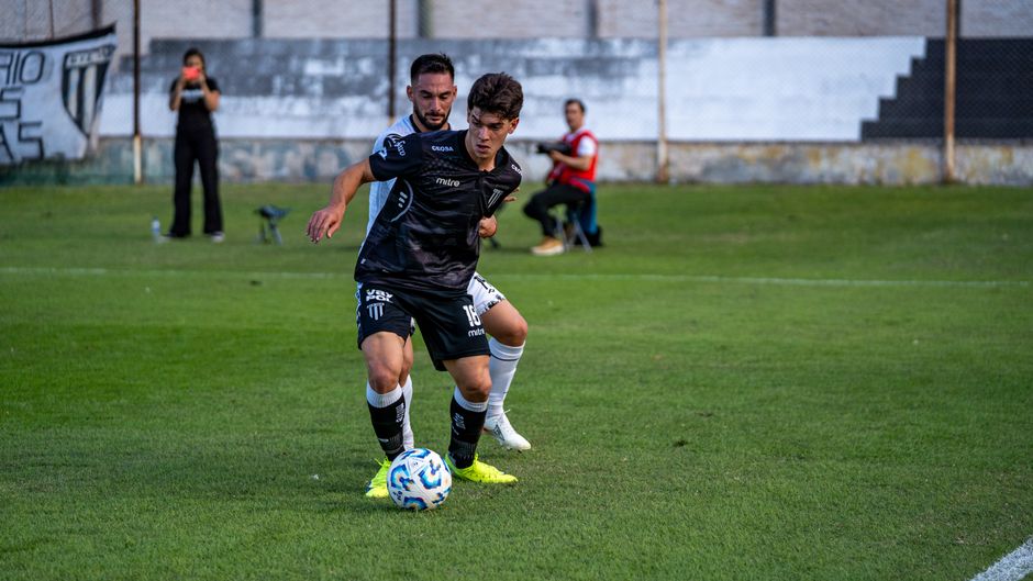 Dynamic action shot of two football players competing on a grassy field during a match.