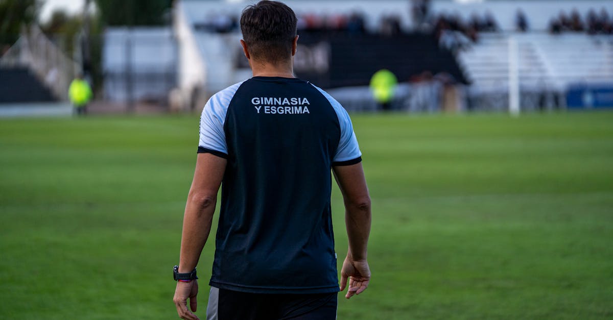 Back view of soccer coach at Gimnasia y Esgrima stadium during a match.