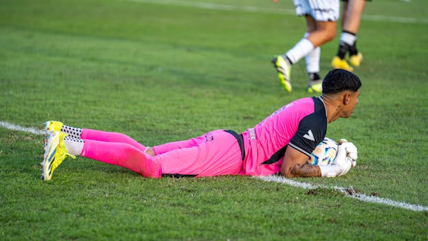 Soccer goalkeeper in pink ready to save, outdoor match setting.