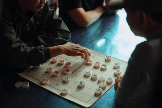 Two men engaged in strategic Chinese chess game creating an intense indoor atmosphere.