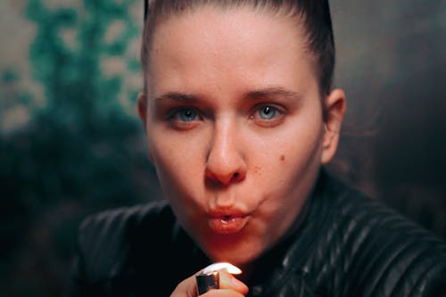 Close-Up Photo of Woman Blowing a Lighter