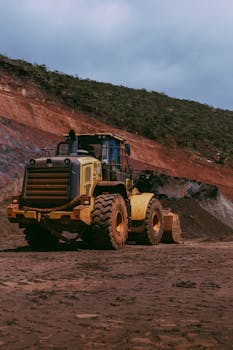 Large yellow bulldozer at a construction site against a rocky hill backdrop.