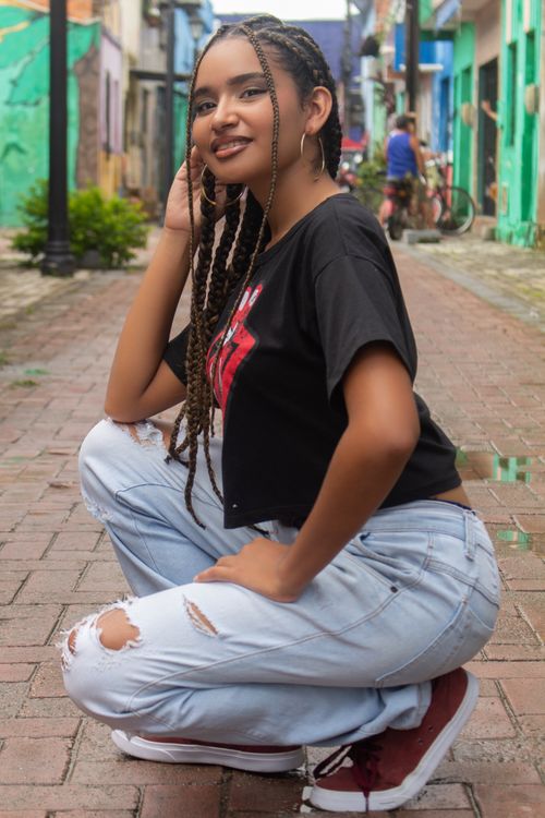 Free Stylish young woman squatting on a colorful street in Ceará, Brazil, wearing casual attire. Stock Photo