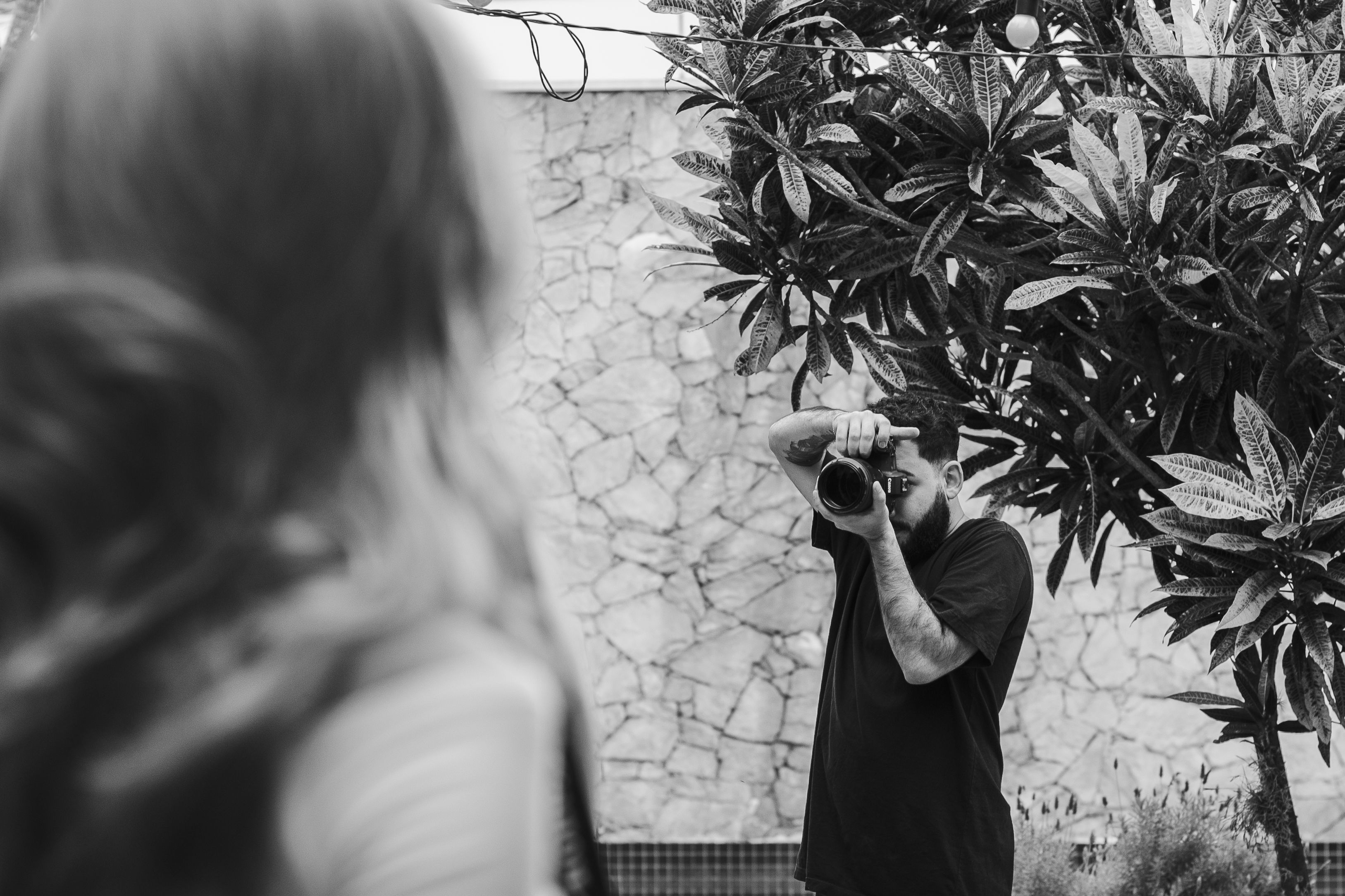 Black and white image of photographer taking a portrait outdoors, focused on the subject.