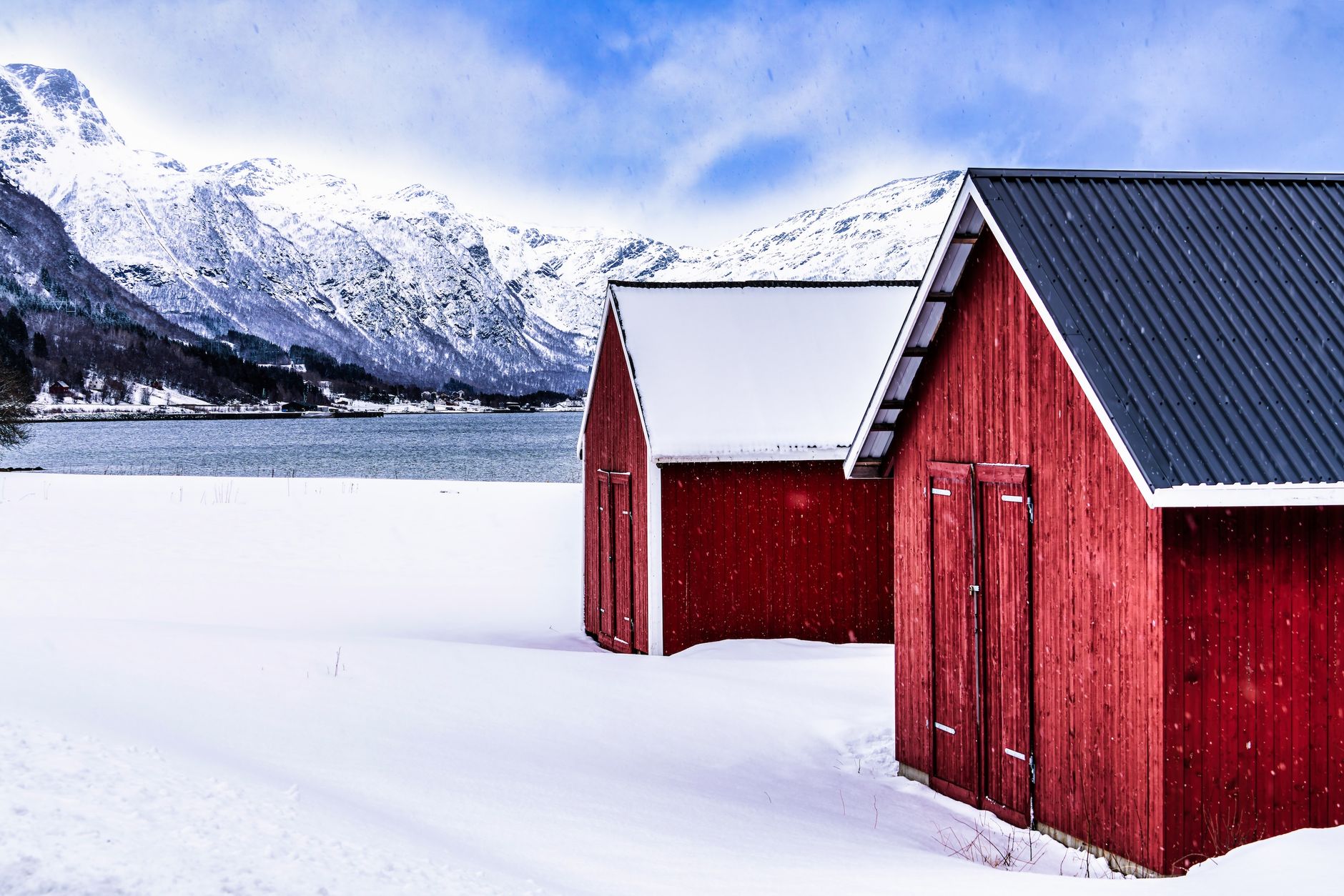 Red cabins amidst snowy mountains in Nordland, Norway