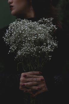 Dark moody portrait of a woman holding a baby's breath bouquet in São Paulo.