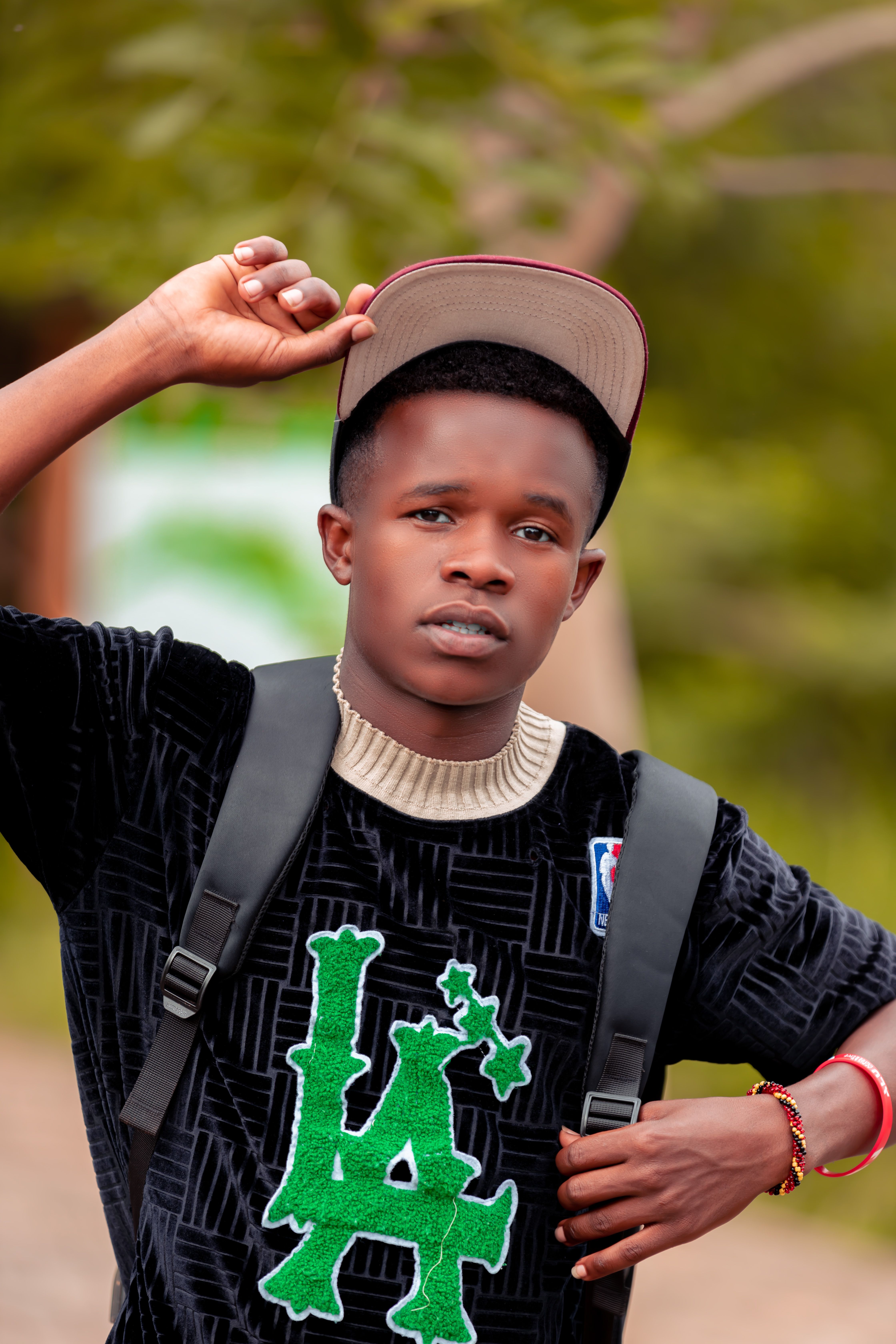 A young man poses in a casual outfit with a confident look outdoors.
