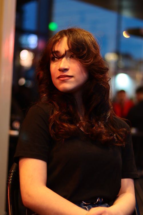 Free A young woman with curly hair gazes thoughtfully in a softly lit evening setting. Stock Photo