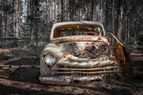Free A decaying vintage car rusting away in a dense forest, symbolizing time's passage. Stock Photo