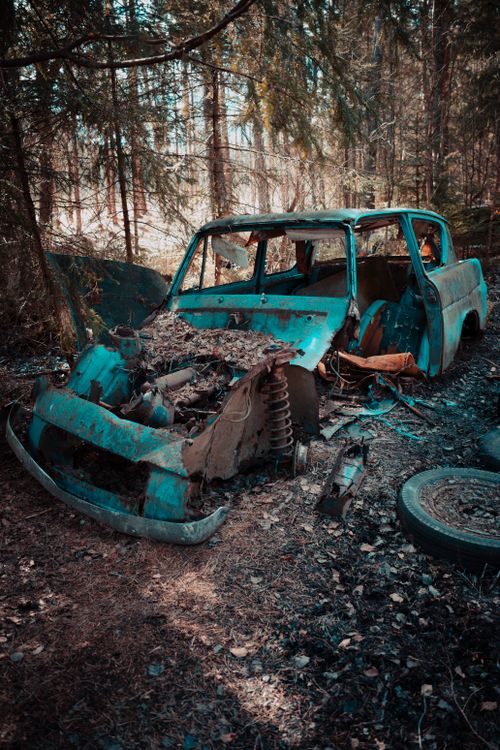 Free A decaying vintage car wreck in a forest, evoking a sense of nostalgia and abandonment. Stock Photo