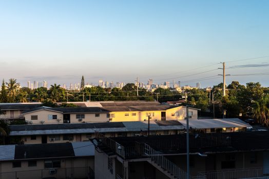View of Miami skyline from Coral Gables at sunset with residential buildings in foreground.
