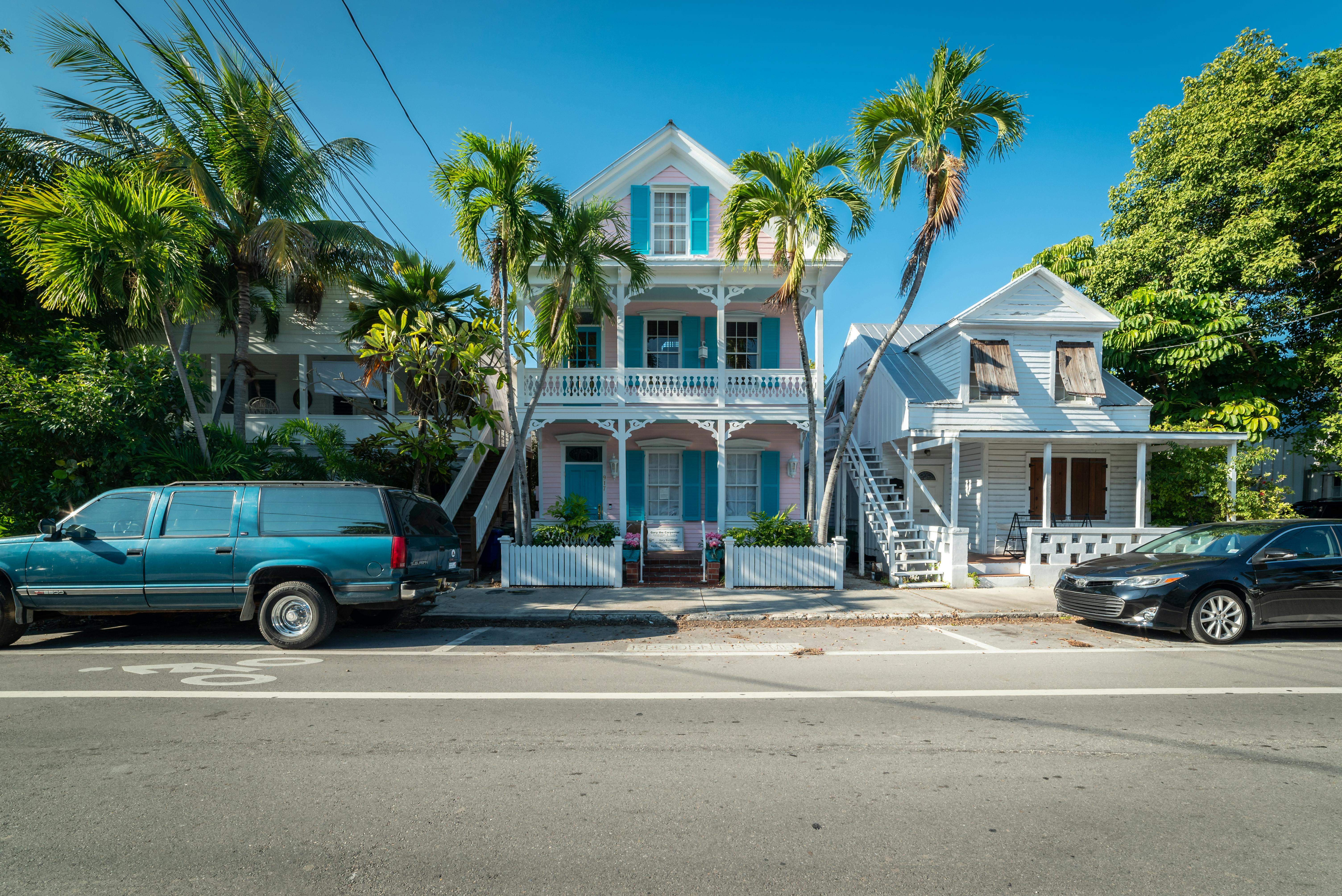 Colorful historic houses with palm trees along a sunny street in Key West, Florida.
