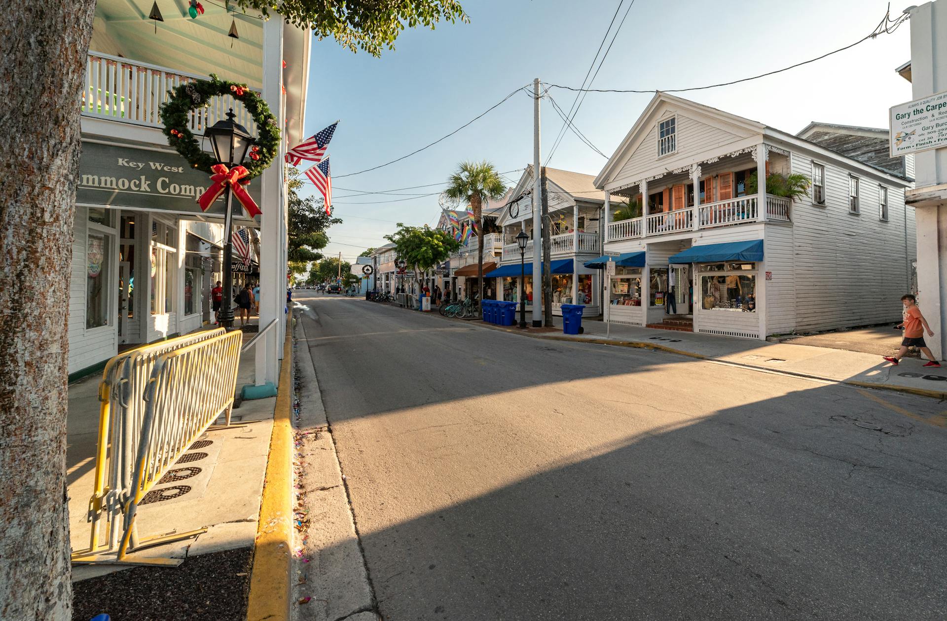 Sunny Key West street scene with American flags and holiday wreaths, capturing the festive charm of the area.