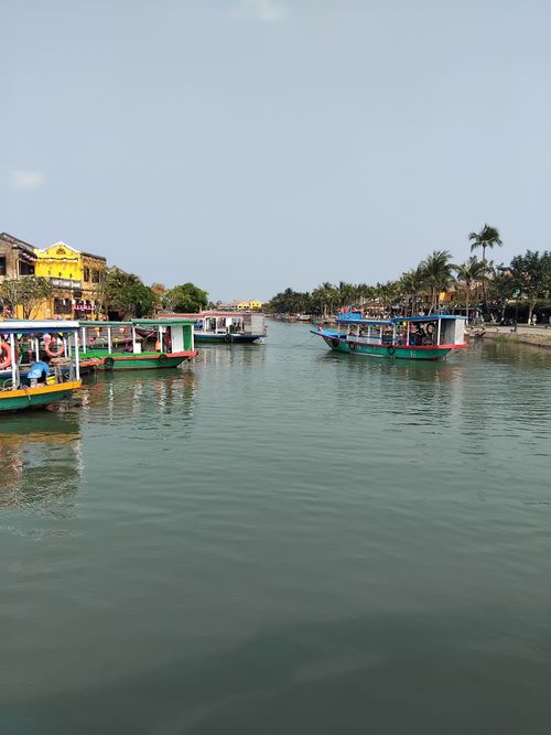 Free Vibrant boats navigate the scenic Thu Bon River in Hoi An, Vietnam, a popular tourism spot. Stock Photo