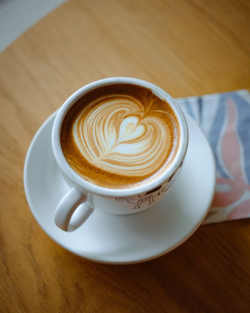 Free Close-up of a latte with a heart-shaped foam art on a wooden table. Stock Photo