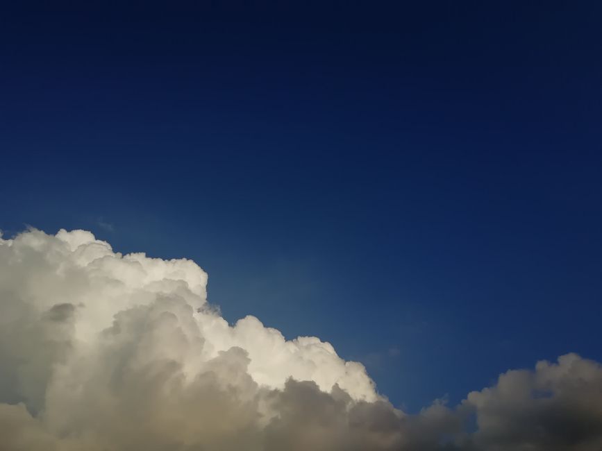 Vivid blue sky with bright, fluffy cumulus clouds, evoking a sense of tranquility and wonder.