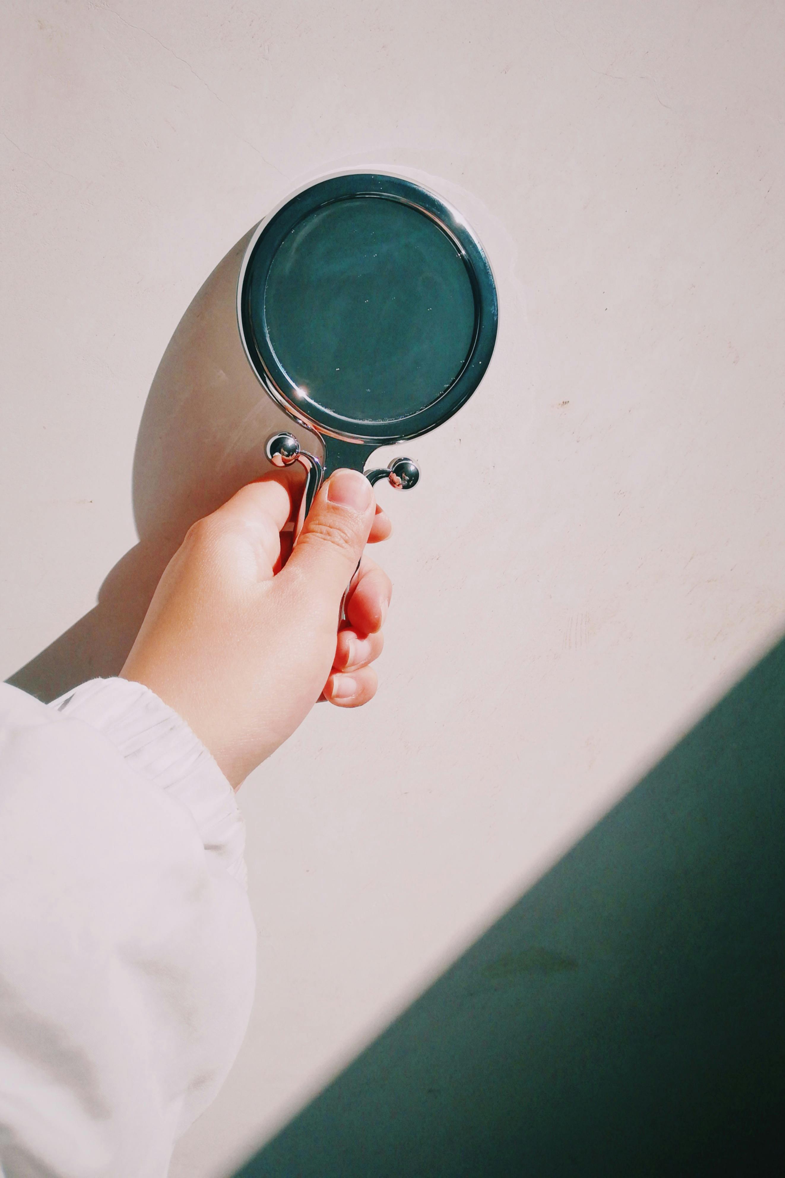 Miễn phí Cận cảnh một bàn tay đang cầm kính lúp với cái bóng đổ trên bề mặt trắng. Ảnh lưu trữ