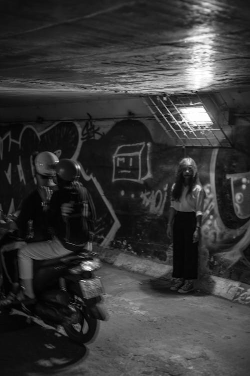 Monochrome Photo of Person Standing Near Graffiti Wall