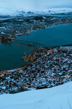Breathtaking aerial view of Tromsø, Norway during twilight with snow-covered landscape.