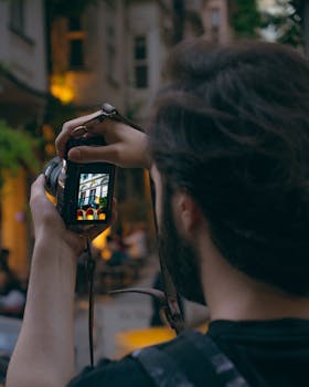 A person photographing urban architecture on a DSLR camera in an evening setting.