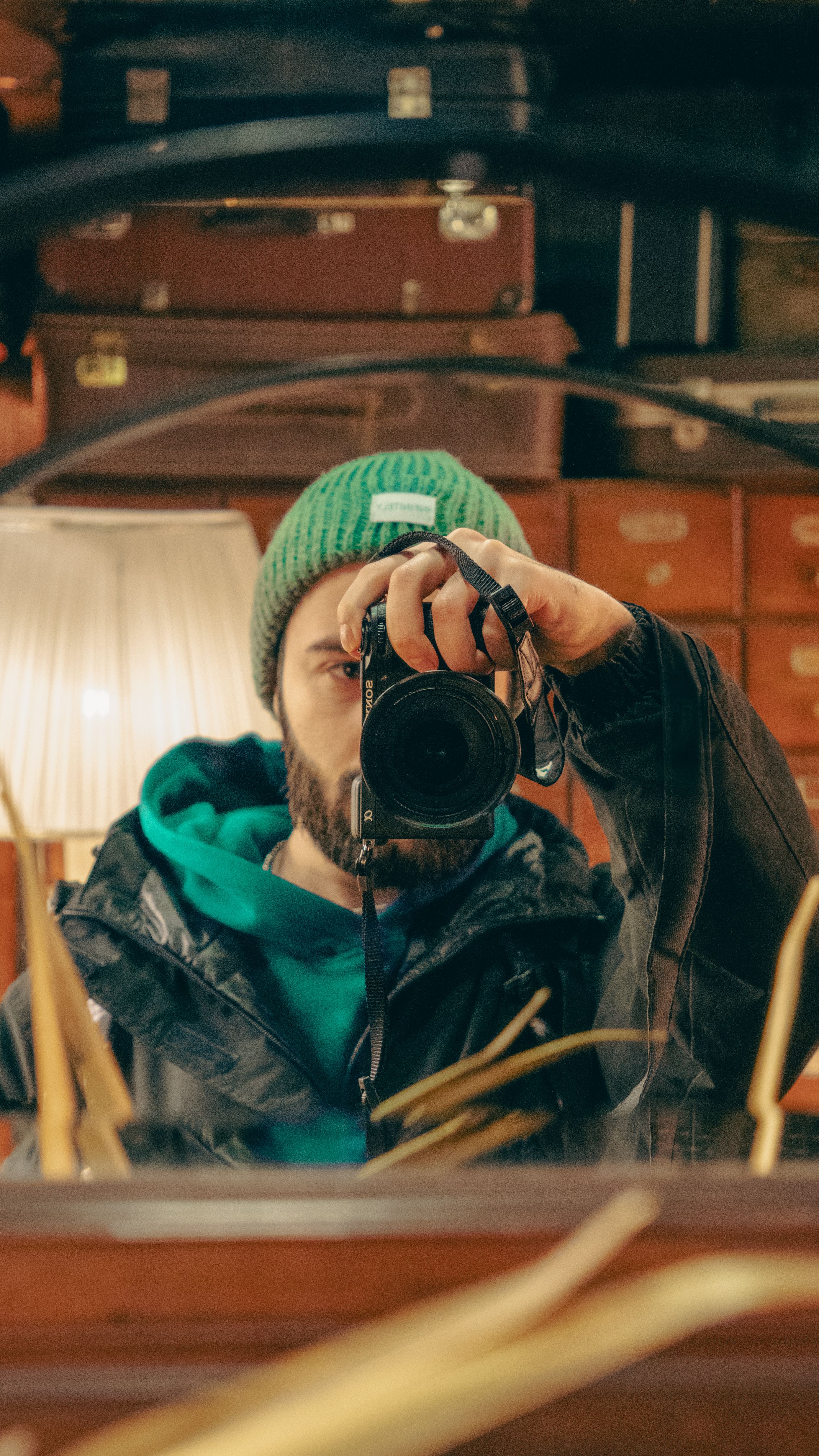 A man takes a mirror selfie in a cozy, vintage room with a camera.