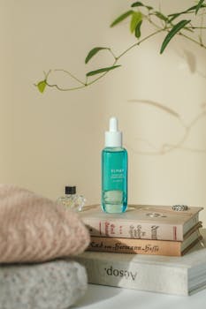 Blue skincare bottle on books with cozy knit background, perfect for lifestyle aesthetics.