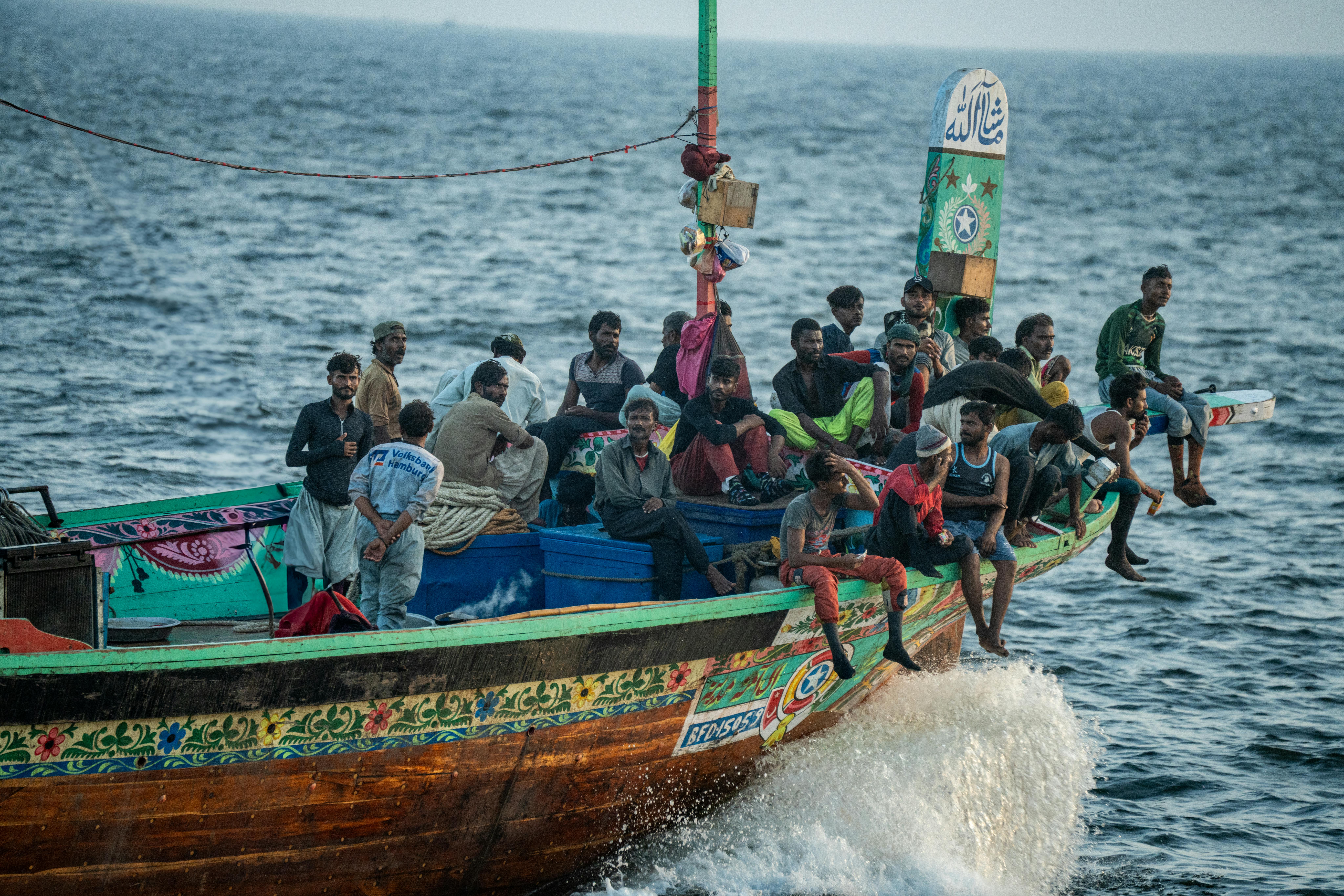A colorful traditional fishing boat with a crew navigating the sea, showcasing cultural and marine life.