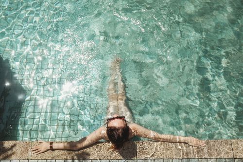 Free A woman enjoying a relaxing swim in a sunlit outdoor pool. Stock Photo