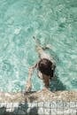 在一个清澈的绿松石游泳池里，一个人享受着阳光明媚的日子游泳