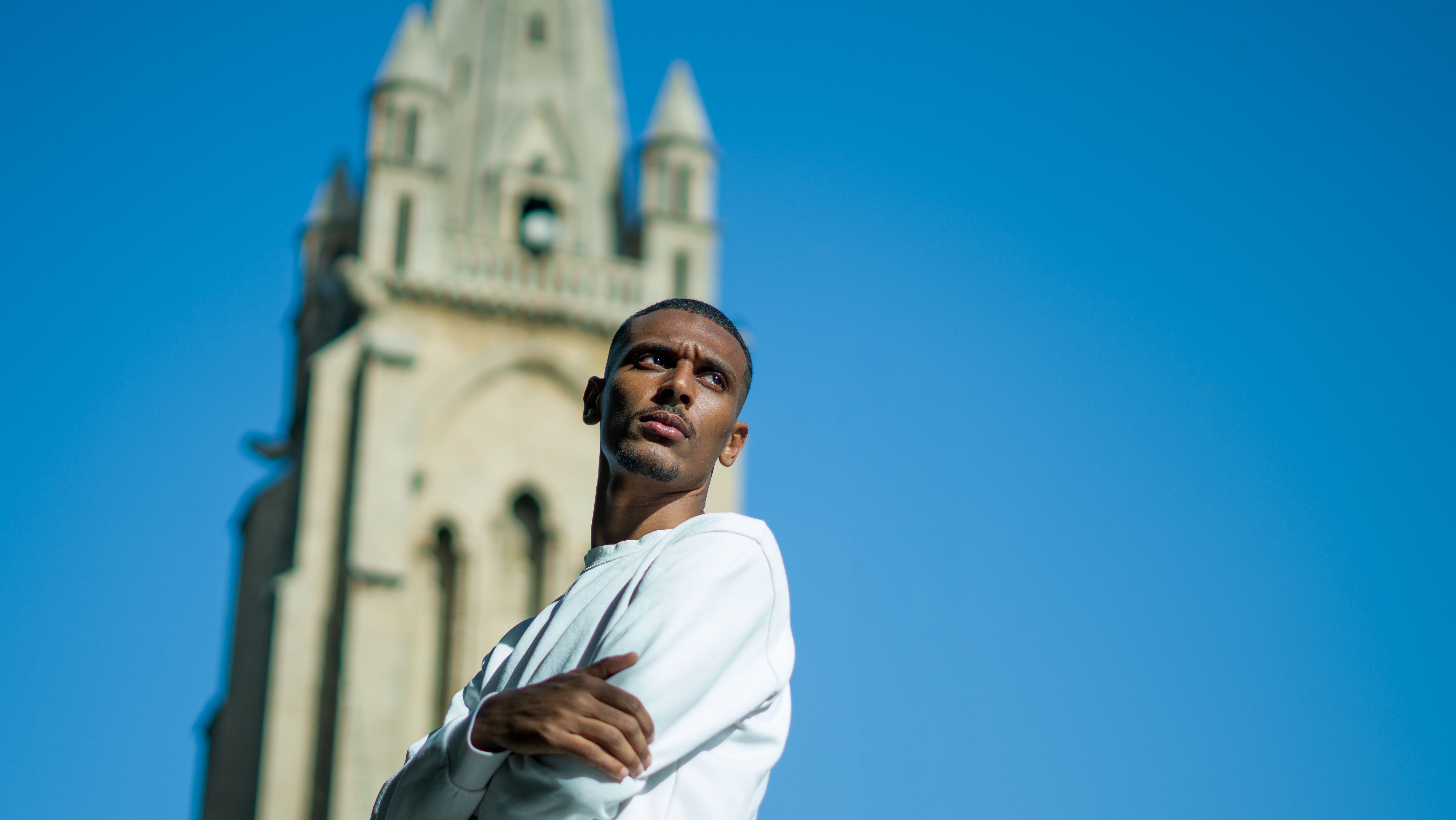Man in Front of Gothic Tower with Blue Sky · Free Stock Photo