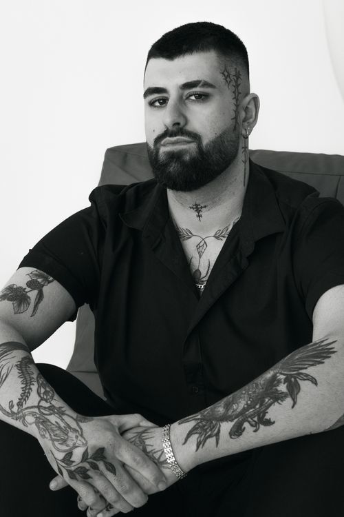 Free A serious, tattooed man poses confidently indoors, exuding a seductive charm. Stock Photo