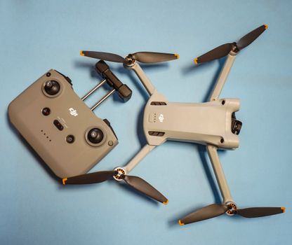 Top-down view of a drone and its controller on a blue surface.
