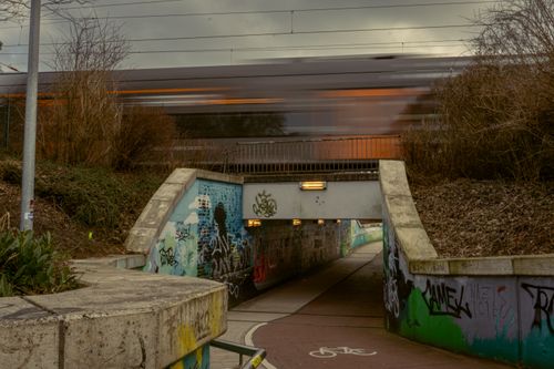 Free Dynamic shot of a train passing over a graffiti-covered underpass in Kamen, NRW, Germany. Stock Photo