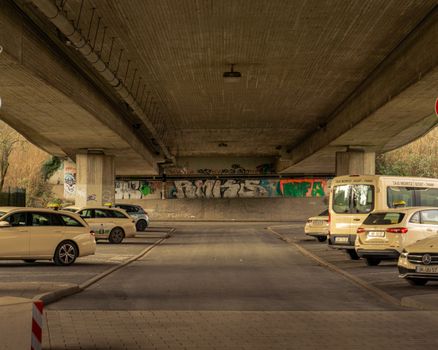 Concrete underpass in Kamen, Germany with parked cars and vibrant graffiti art.