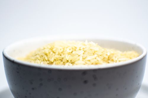 Free A close-up view of uncooked white rice in a speckled ceramic bowl on a light background. Stock Photo