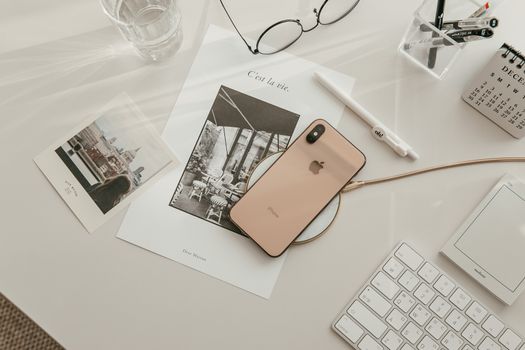 Aesthetic workspace featuring a smartphone, keyboard, and stationery in a warm, minimalist setup.