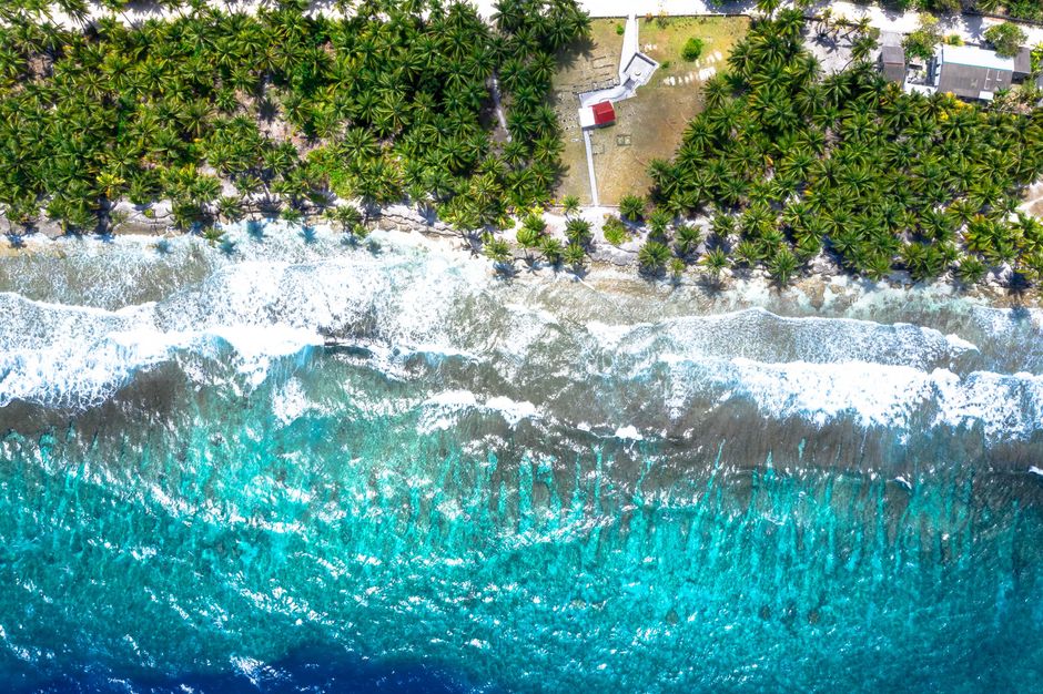 Stunning aerial view showcasing turquoise water waves crashing onto a lush tropical beach.