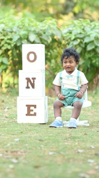 Adorable toddler sits with birthday blocks spelling 'ONE'.