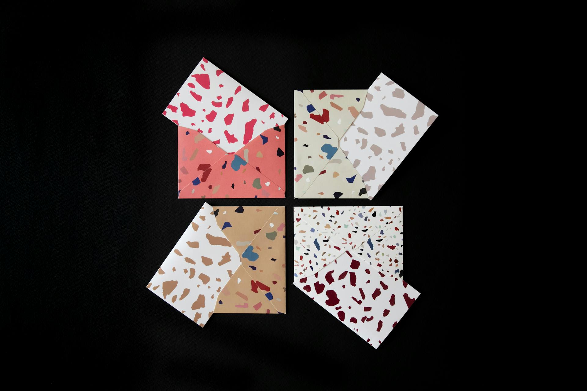 Stylish terrazzo patterned envelopes in vibrant colors on a black background.
