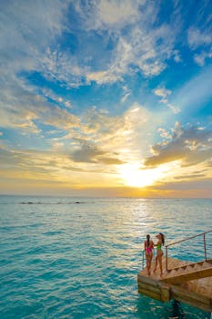 两个人在热带码头欣赏壮丽的海洋日落