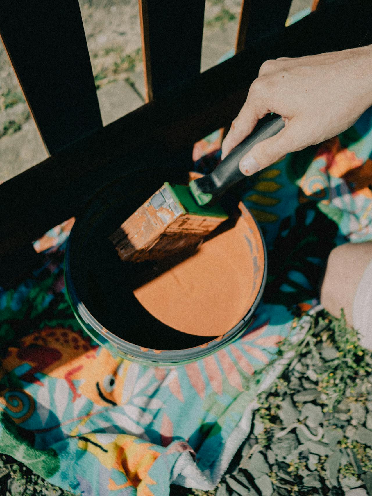 Mano che applica olio protettivo su una recinzione di legno all'aperto