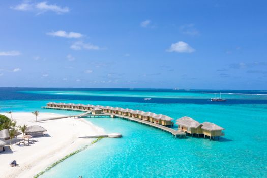 Stunning beachfront resort with overwater bungalows and turquoise waters, perfect for a summer vacation.