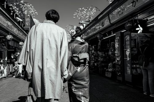 Free A couple in traditional Japanese attire walking through a bustling street in Taito City, Tokyo. Stock Photo